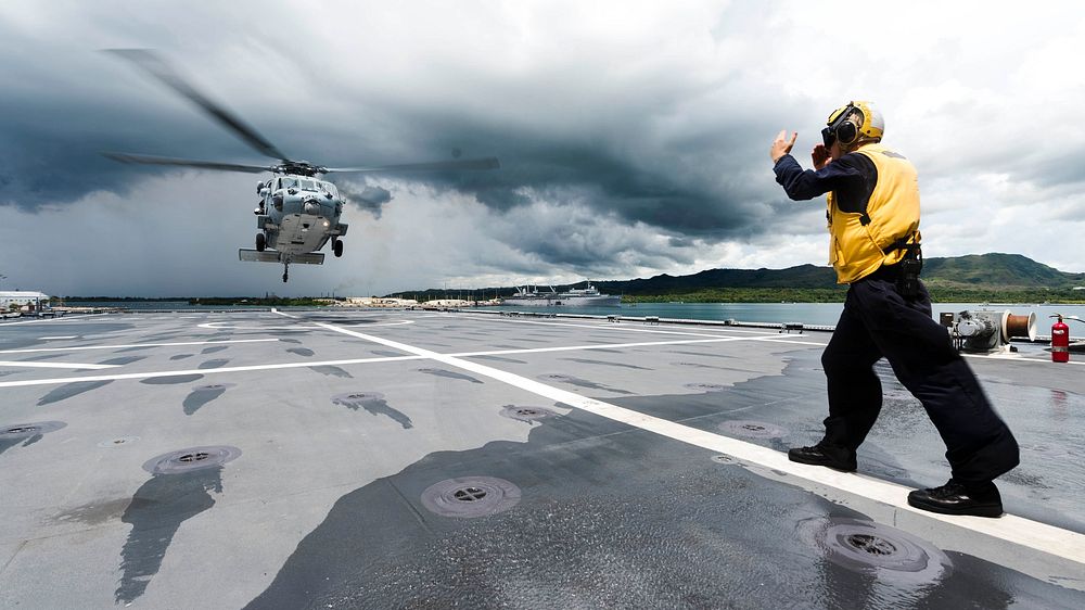 Boatswain's Mate 2nd Class Paul Coombs directs an MH-60S Seahawk helicopter to the flight deck aboard the littoral combat…
