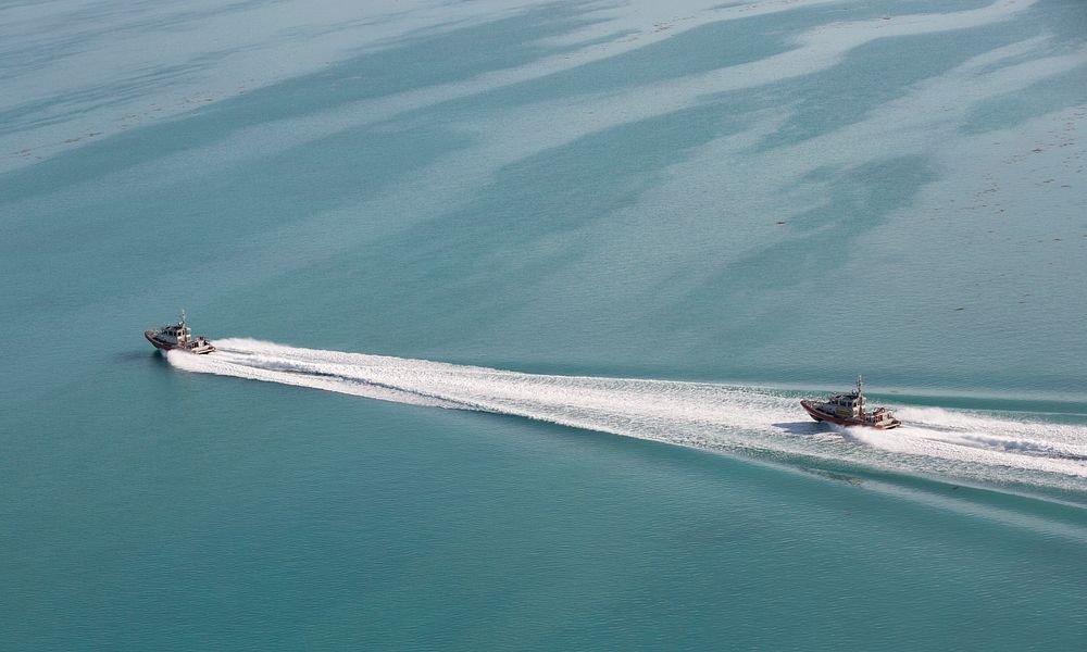 Two U.S. Coast Guard vessels patrol in tandem as they cruise over now calm, but murky, waters of the Florida Keys after…