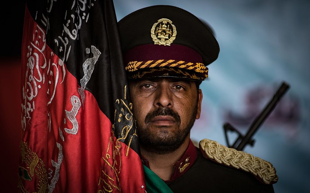An Afghan National Security and Defense Forces honor guardsman stands beside a ceremonial flag during the UH-60 Black Hawk…