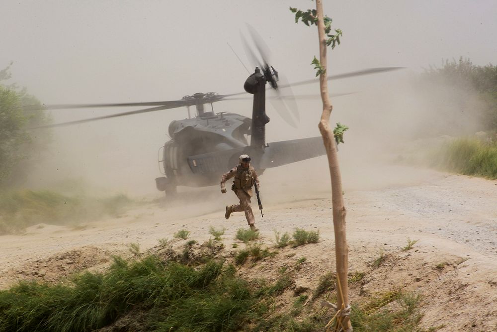 U.S. Navy Hospital Corpsman 3rd Class Simon Trujillo runs for cover as a UH-60 Black Hawk helicopter prepares to takeoff…