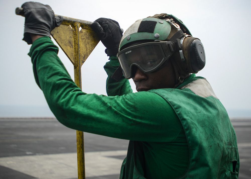 U.S. Navy Airman Christopher Francis, from Atlanta, holds a push-back bar as he waits to conduct flight operations aboard…