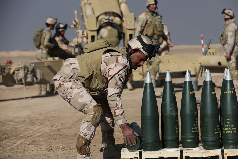 An Iraqi army soldier picks up a round for an M198 155 mm howitzer as part of training from French forces at the Besmaya…