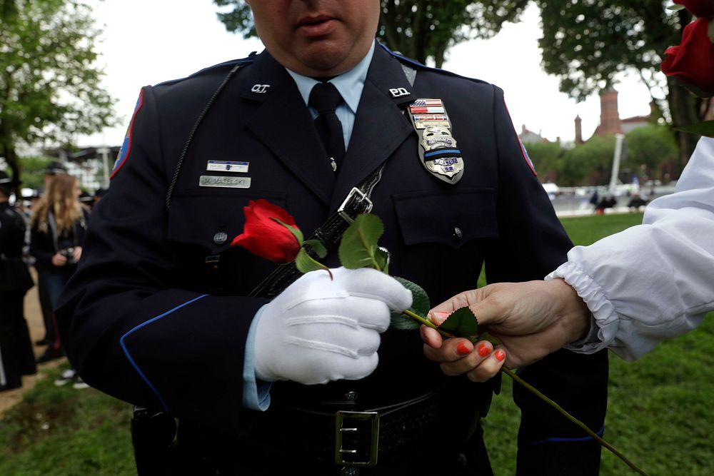A police officer grabs a rose as he returns to the line of family escorts at the start of the 31st Annual Candlelight Vigil…