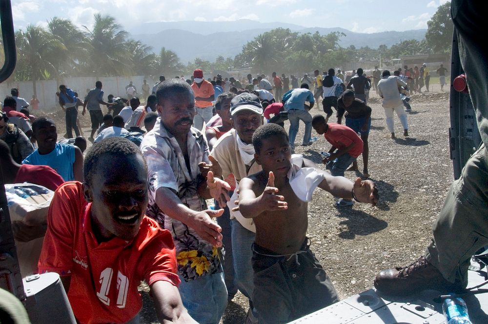 Haitian citizens reach for water being distributed by U.S. Navy air crewmen in Port-au-Prince, Haiti, Jan. 16, 2010.