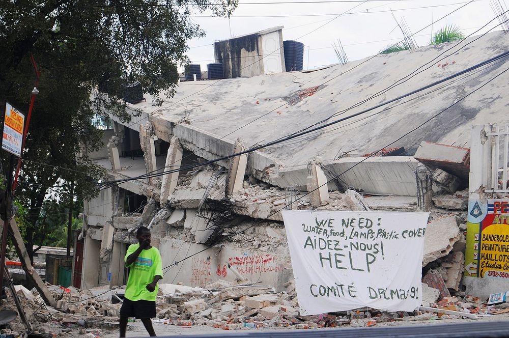 A Haitian man walks past a sign requesting help and supplies in Port-au-Prince, Haiti, Jan. 19, 2010.