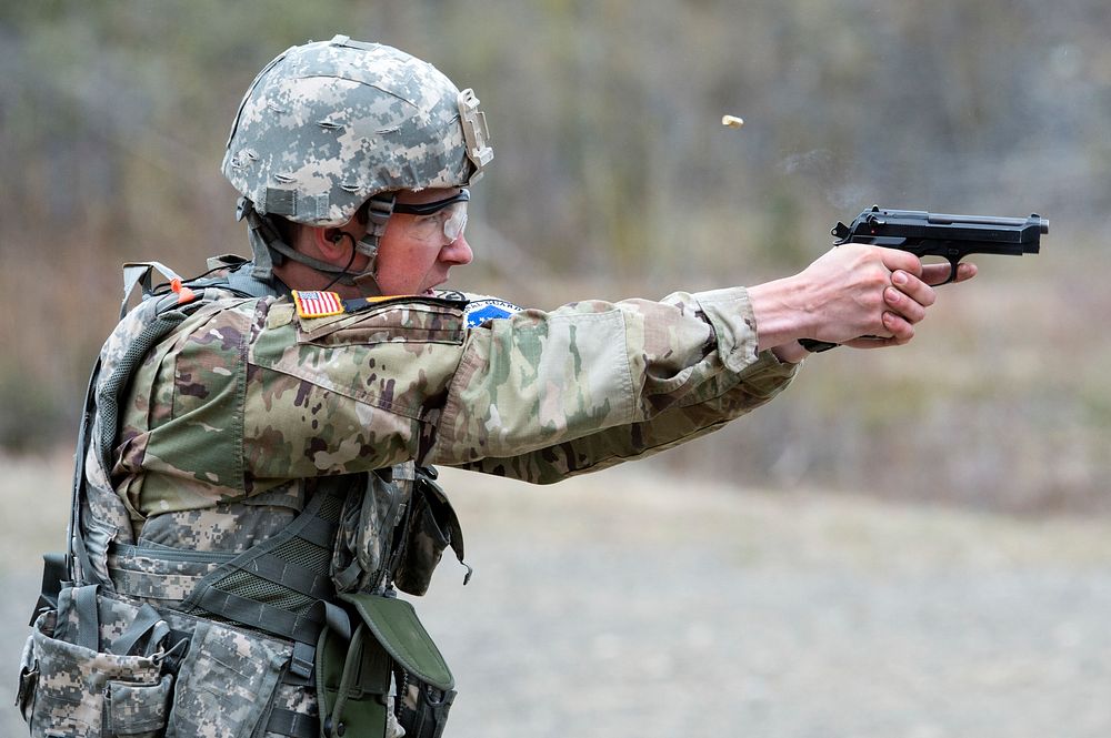 U.S. Army Spc. Tucker Zimmerman with the Montana Army National Guard fires a M9 pistol while competing in a maneuver and…