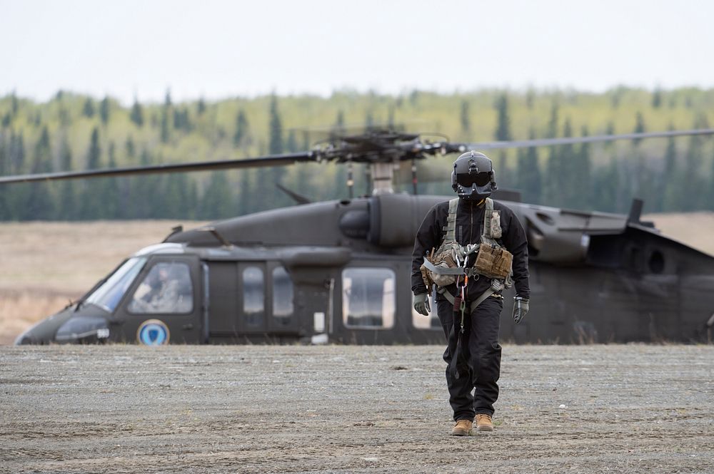 A U.S. Army UH-60 Black Hawk helicopter crew chief with the Alaska Army National Guard approaches range personnel to confer…