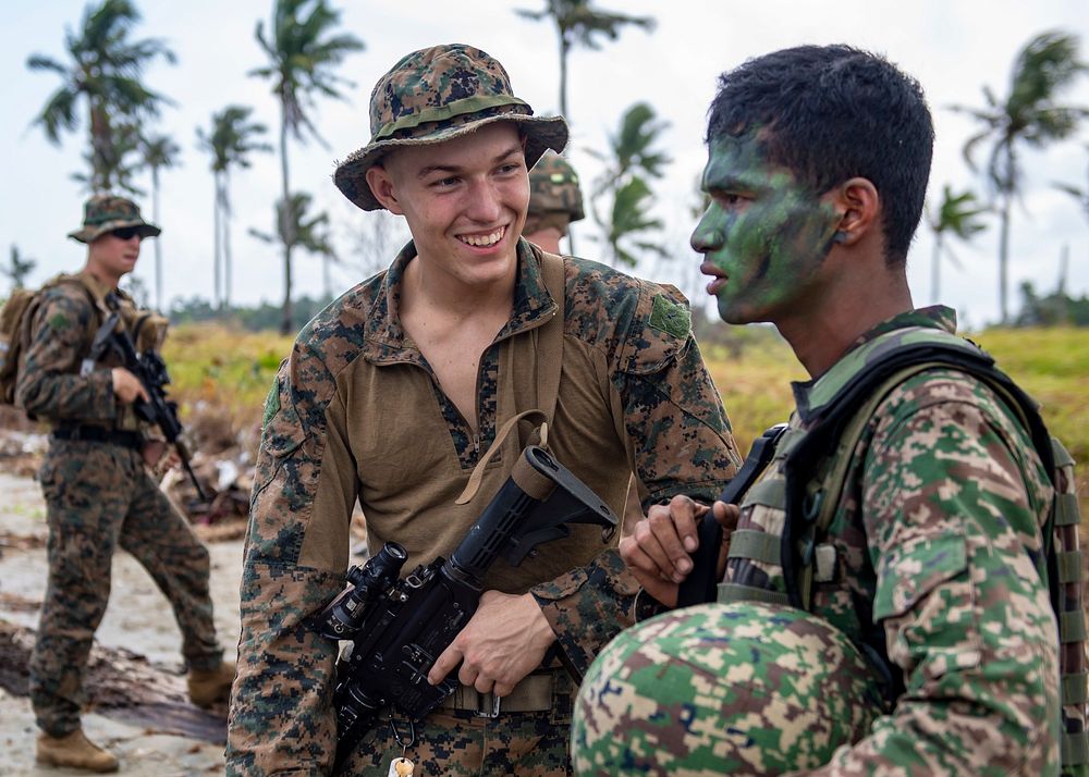 U.S. Marine Corps Pfc. Erik Anderson speaks with a Royal Malaysian marine after completing a simulated beach assault during…