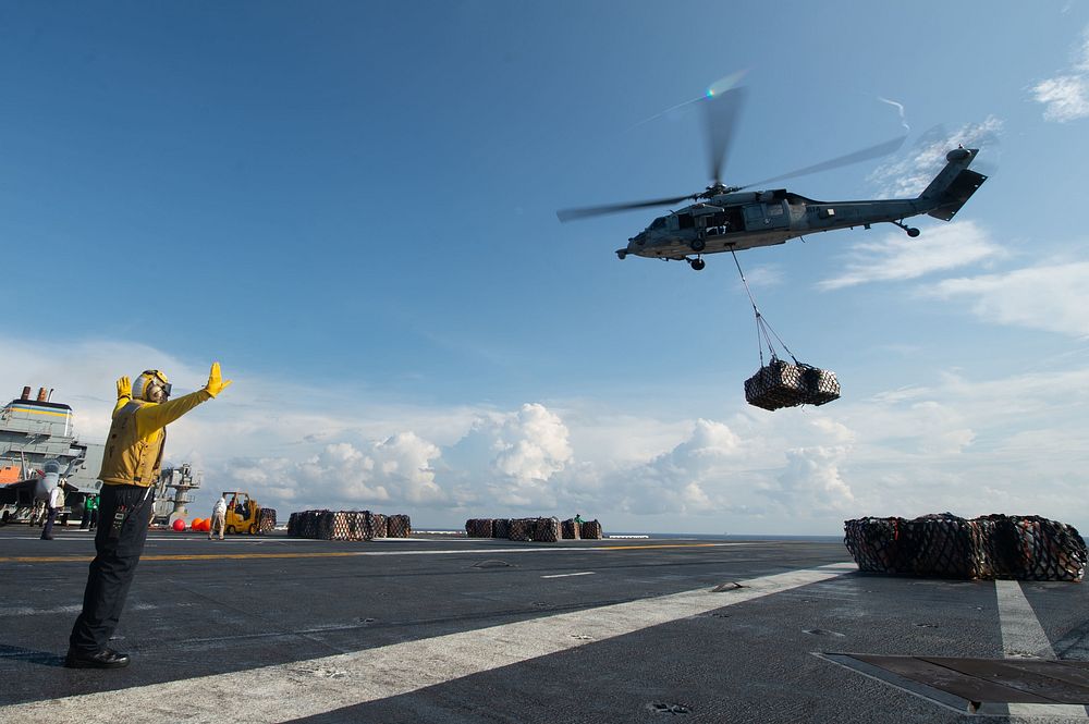 A U.S. Navy MH-60S Sea Hawk, with Helicopter Sea Combat Squadron (HSC) 14, prepares to offload pallets of cargo onto the…