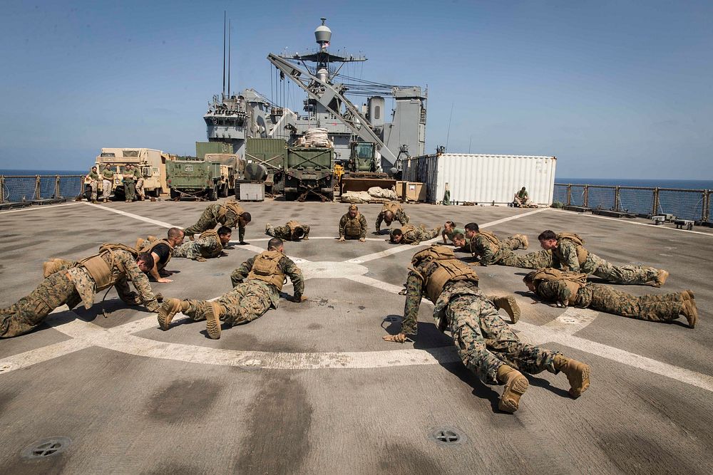 U.S. Marines with the 13th Marine Expeditionary Unit (MEU), perform burpees as a group during a physical training event for…