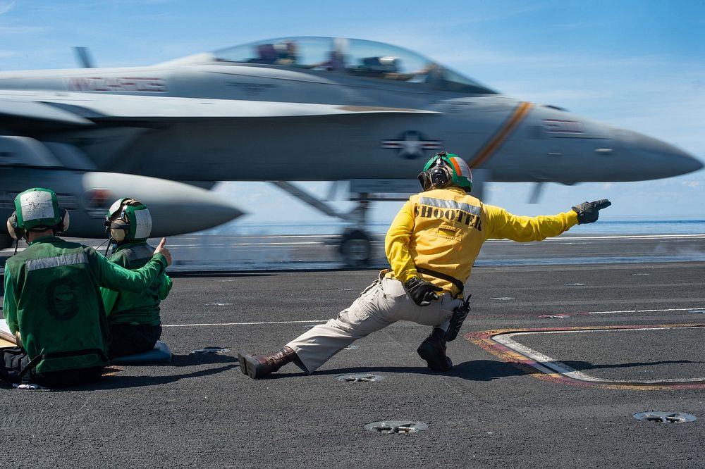U.S. Navy Lt. Eric Jensen, from Austin, Texas, signals an EA-18G Growler assigned to Electronic Attack Squadron (VAQ) 133 to…