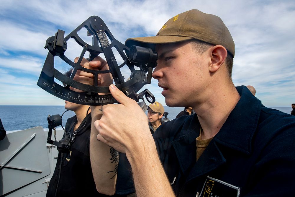 U.S. Navy Quartermaster Seaman Ethan Bracket uses a stadimeter on the starboard bridge wing to gauge the distance between…