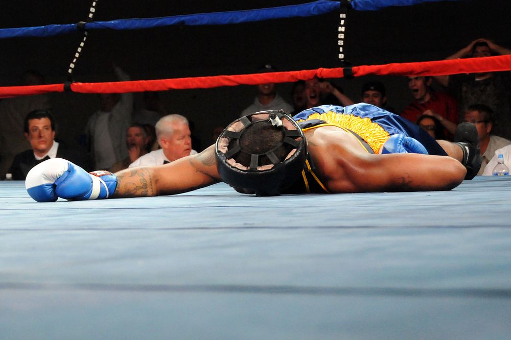 U.S. Navy Aviation Machinist Mate Tyron Hunter is knocked out on the canvas by U.S. Army Private First Class Charles…