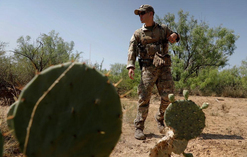 A U.S. Border Patrol Search, Trauma, and Rescue (BORSTAR) agent searches dense brush for "sign" as he and fellow Border…