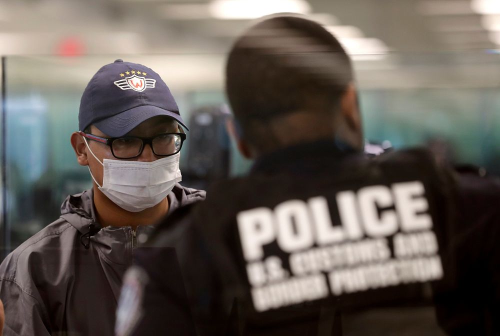 An officer with U.S. Customs and Border Protection Office of Field Operations, right, clears an international traveler…