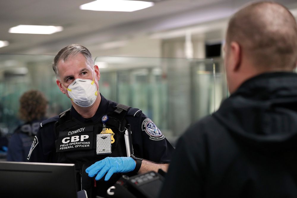 An officer with U.S. Customs and Border Protection Office of Field Operations reviews travel documents of an arriving…