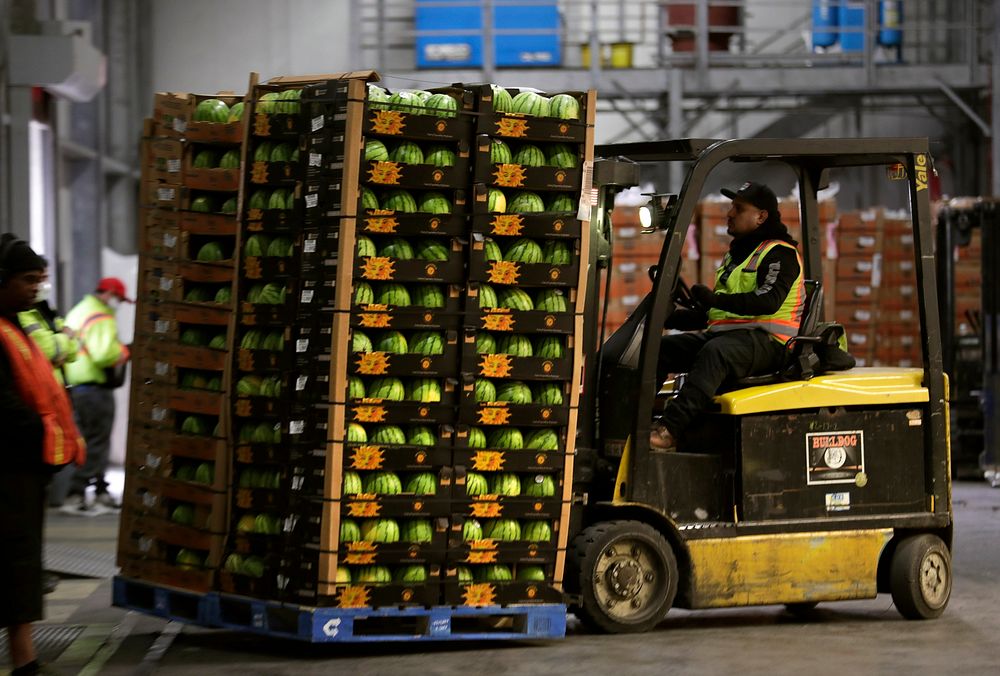 A forklift operator shuttles a pallet loaded with boxes of watermelons to an awaiting truck as fruit shipments arrive at the…