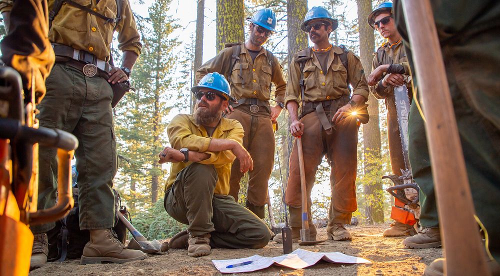 North Complex. Photo depicts crew members strategizing around a map in the field at the North Complex. Forest Service photo…