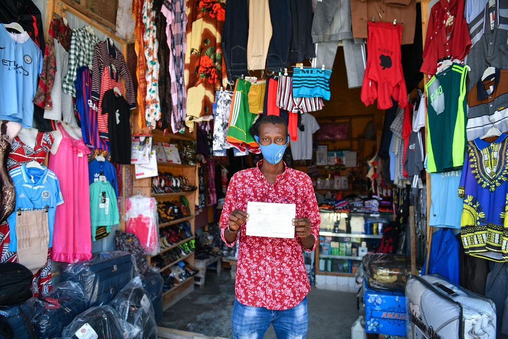 Shop owner holds out his COVID-19 certificate at his shop after getting the COVID-19 jab in Mogadishu, Somalia on 30 August…