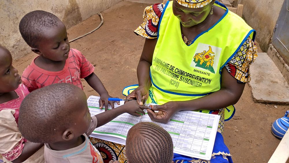 Community health worker, Fatimatou, gives malaria prevention medication to a child.