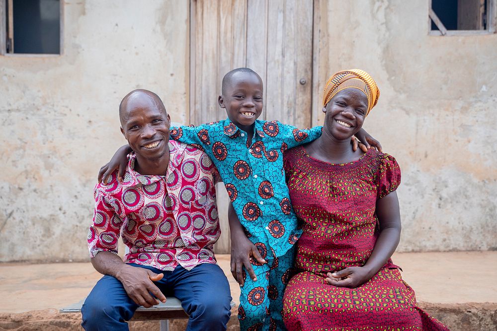 Family outside their home for a photo after pregnant wife and mother received malaria prevention medication.