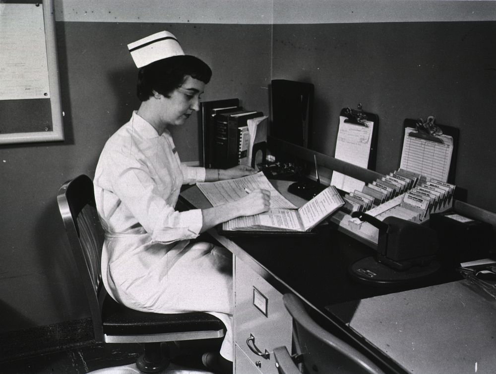 Clinical Center Nurse at her Desk in a Nursing Unit. Original public domain image from Flickr