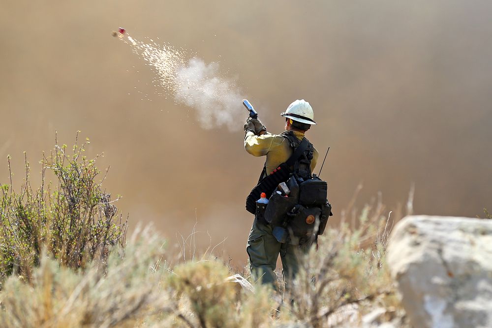 Bear Fire. A firefighter with the Wolf Creek Hotshots uses a pistol-style flare launcher during a firing operation on the…