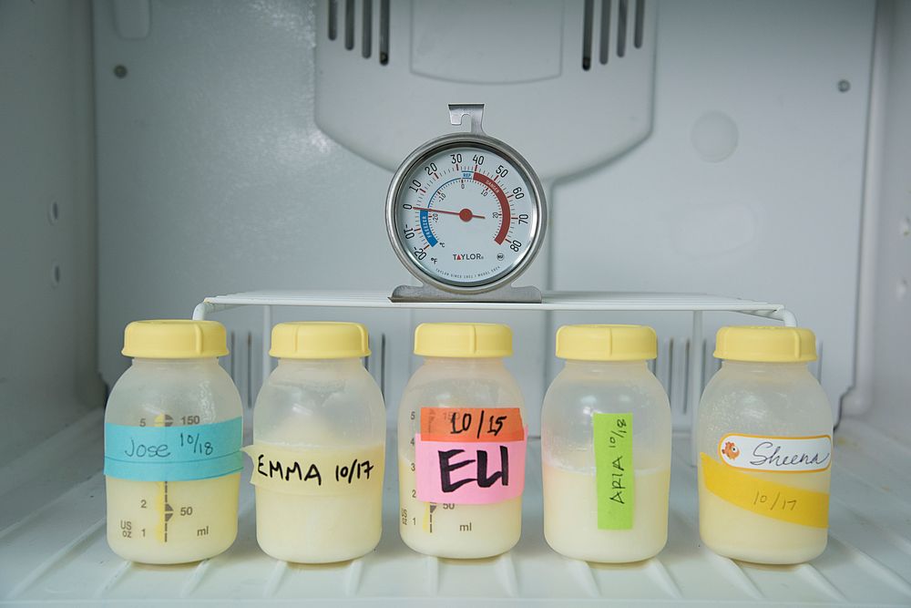 Bottles of frozen breastmilk shown in the freezer with the baby’s name and date labels clearly visible.