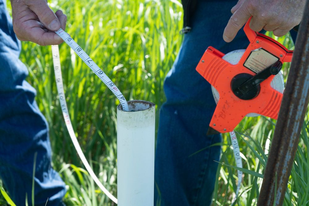 Measuring the depth to the water table using a well drilled specifically for the purpose.