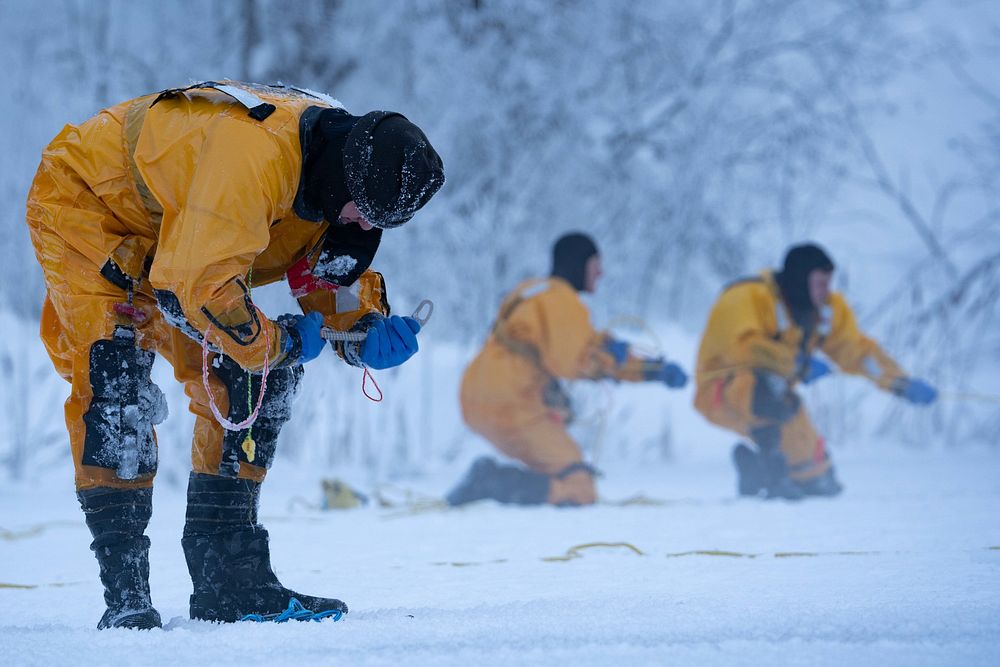 Karl Schultz, left, a firefighter for the 673d Civil Engineer Squadron, prepares an ice anchor during ice-rescue training at…