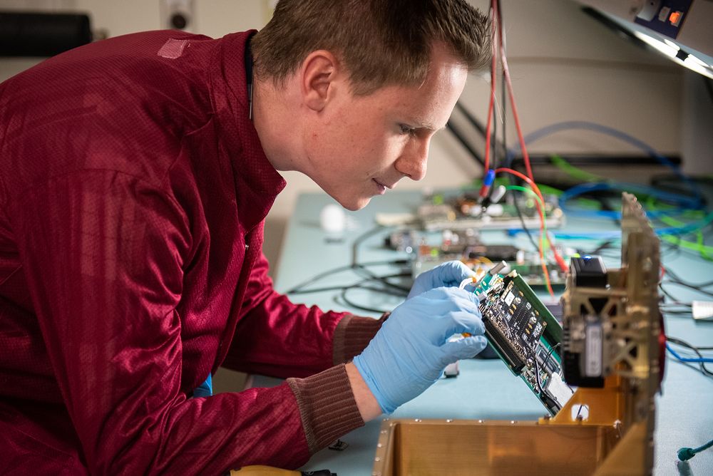 Thomas Bradshaw, Sandia electrical engineer and flight software lead, inspects a computer board for an upcoming remote…