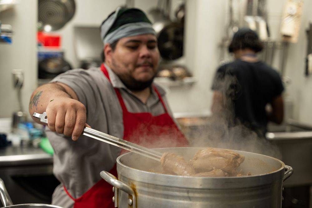 Raphael Bravo, a trainer advocate for cooking, baking and service with Café Reconcile, prepares some food before the…