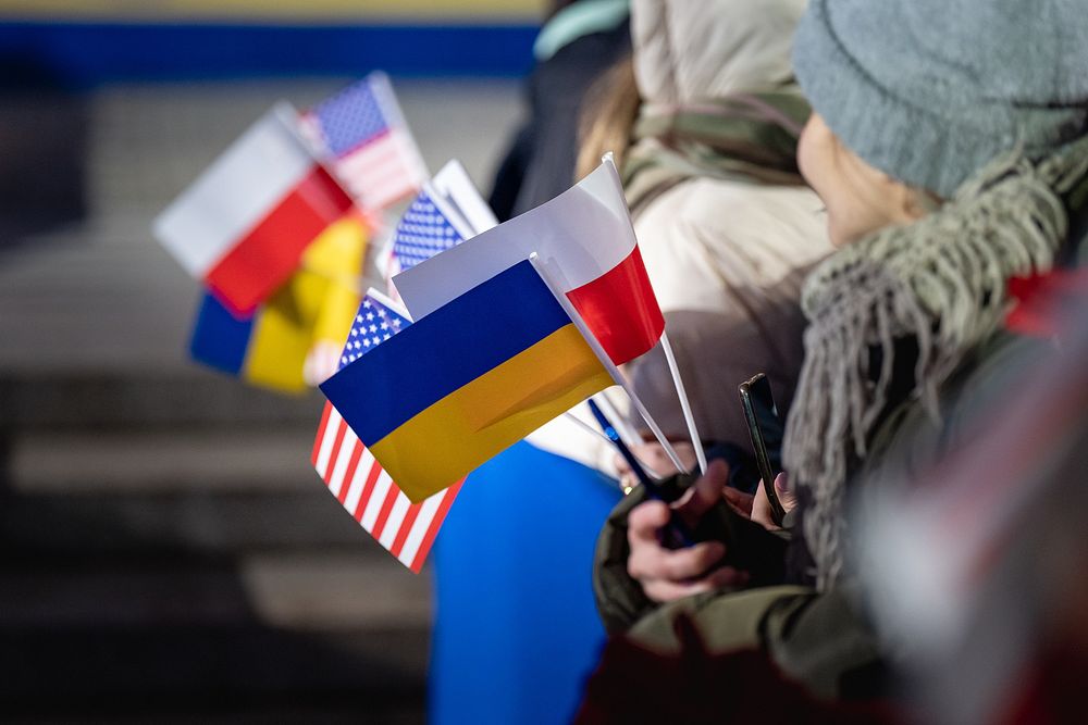 Attendees hold American, Polish, and Ukrainian flags as President Joe Biden delivers remarks, Tuesday, February 21, 2023, at…