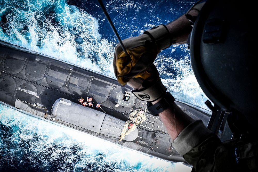 An East-Coast-based U.S. Naval Special Warfare Operator (SEAL) hoists down to Ohio-class guided-missile submarine USS…