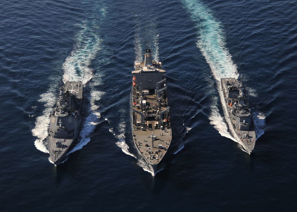 The Military Sealift Command fleet replenishment oiler USNS Tippecanoe (T-AO 199), center, refuels the Japanese Maritime…