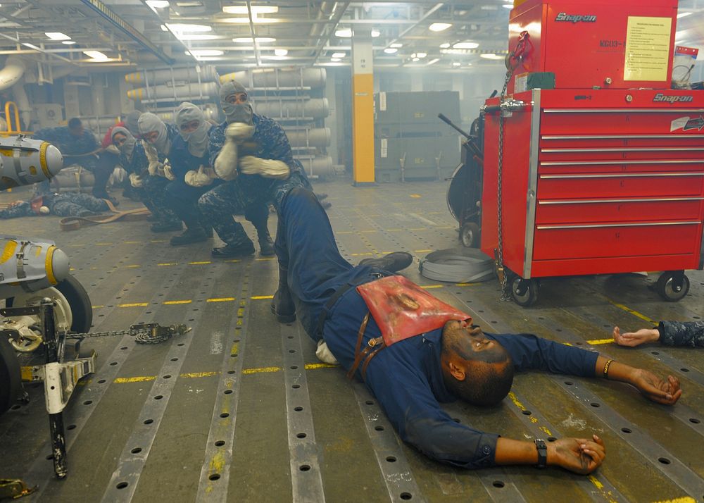 U.S. Sailors act as casualties of a simulated explosion aboard the aircraft carrier USS Abraham Lincoln (CVN 72) as a fire…