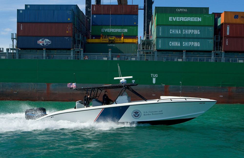 U.S. Customs & Border Protection Air & Marine Boat patrols past shipping containers.