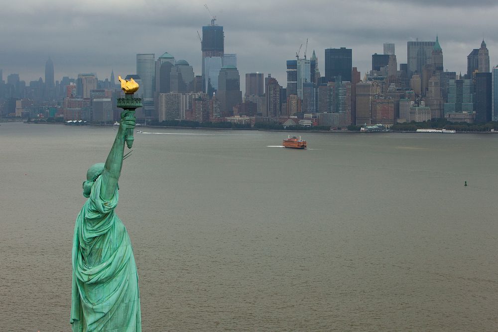 The Statue of Liberty stands off of Manhattan New York.