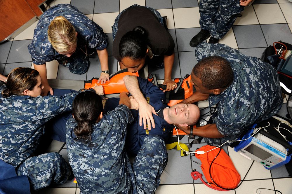 U.S. Navy hospital corpsmen roll Lt. Todd Leroux onto a stretcher during an emergency medical drill aboard the Nimitz-class…