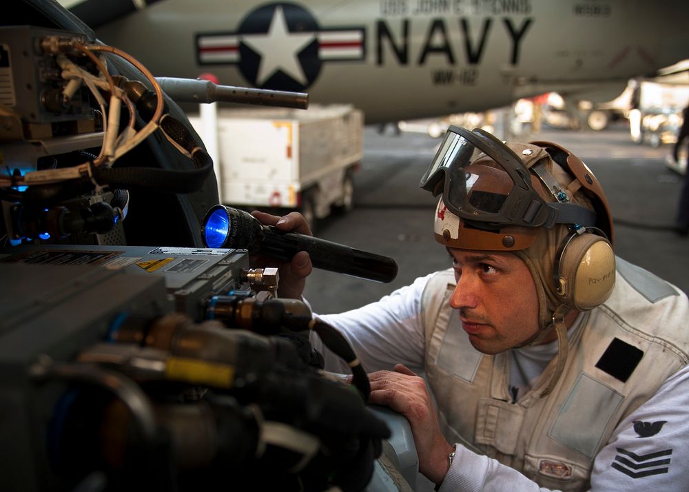 U.S. Navy Aviation Electronics Technician 1st Class Christopher Linares searches for foreign object debris in an MH-60R Sea…