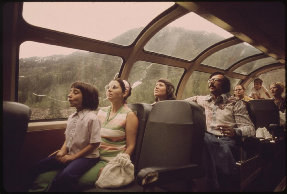 Passengers enjoy the view in the observation car aboard Expo '74 as the passenger train passes through the Cascade Mountain…