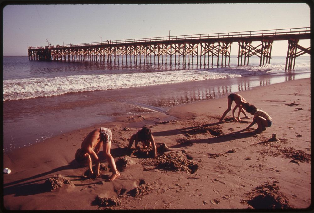 Youngsters play in the sand at the Gaviota State Beach. In the background is the pier, June 1975. Photographer: O'Rear…