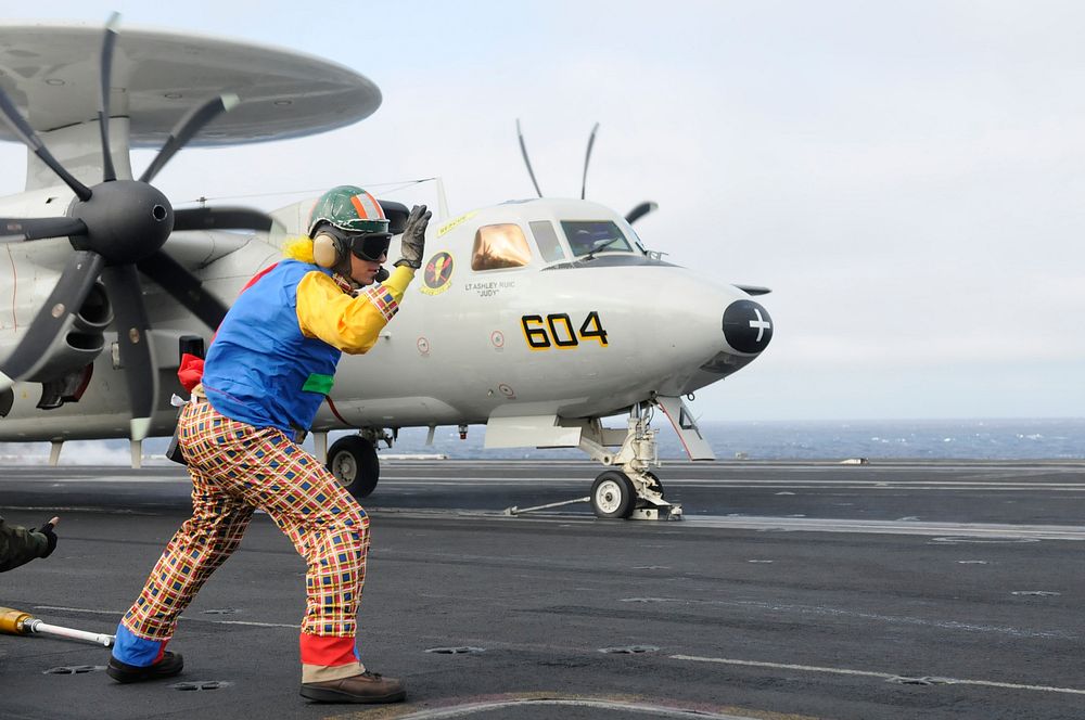 U.S. Navy Lt. Douglas Kay, an aircraft launch and recovery equipment officer, wears a clown suit while launching an E-2C…