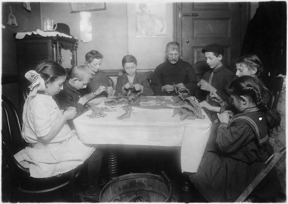 Making garters. A Jewish family and neighbors working until late at night, February 1912. Photographer: Hine, Lewis.…