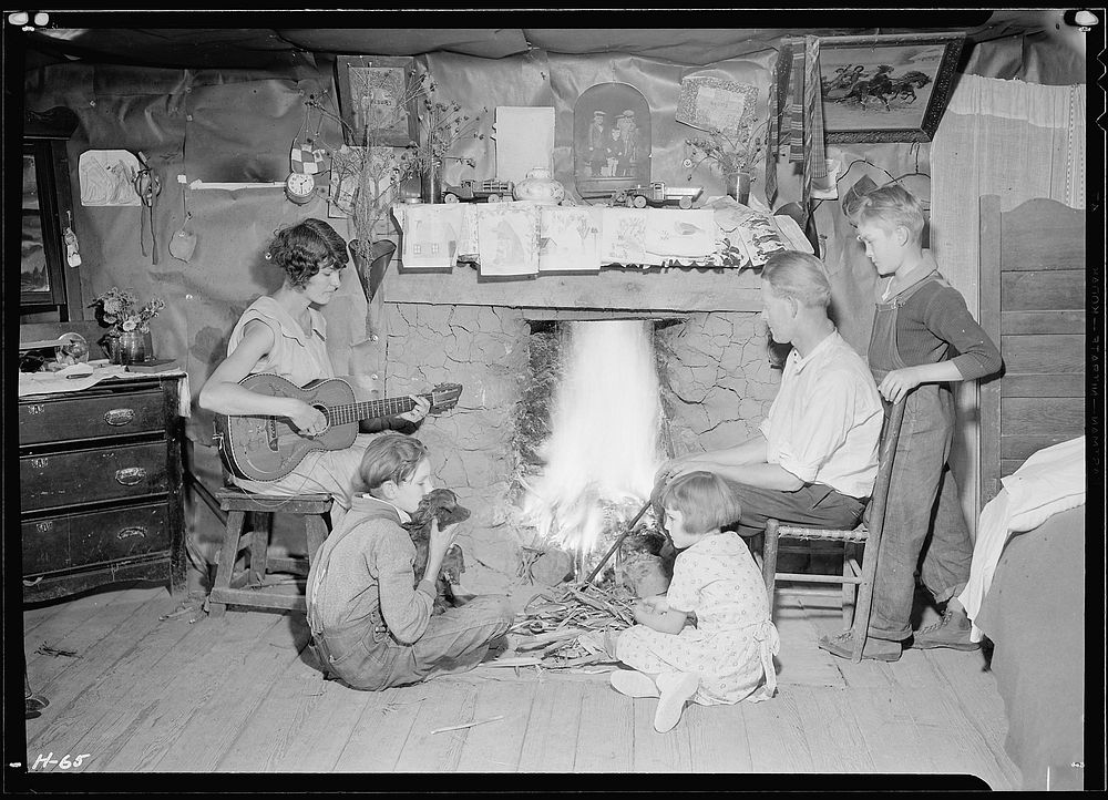 The Glandon family around the fireplace in their home at Bridges Chapel near Loydston [sic], Tennessee. Glandon's wife plays…
