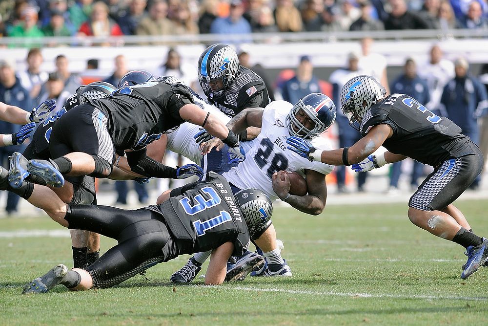 Charles Ross, center, a running back for Rice University, is dragged down by Falcon defenders with the U.S. Air Force…