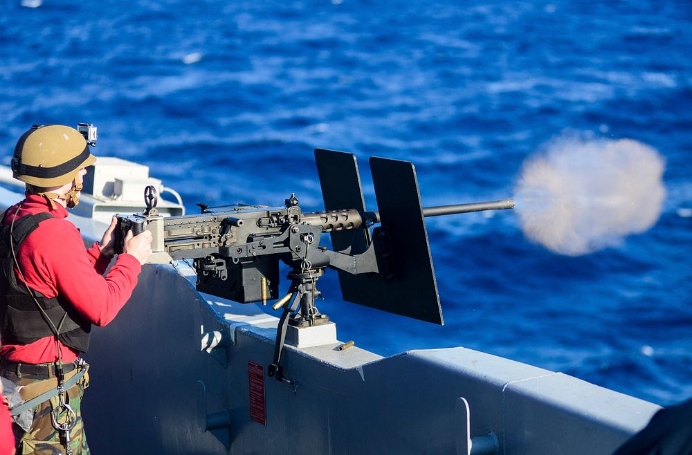 U.S. Navy Gunner's Mate 3rd Class Joshua Smith fires a .50-caliber machine gun during a live-fire exercise aboard the…
