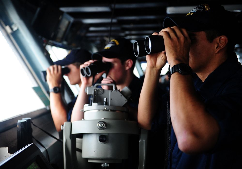 U.S. Navy midshipmen observe surface contacts through binoculars June 10, 2013, aboard the aircraft carrier USS George H.W.…