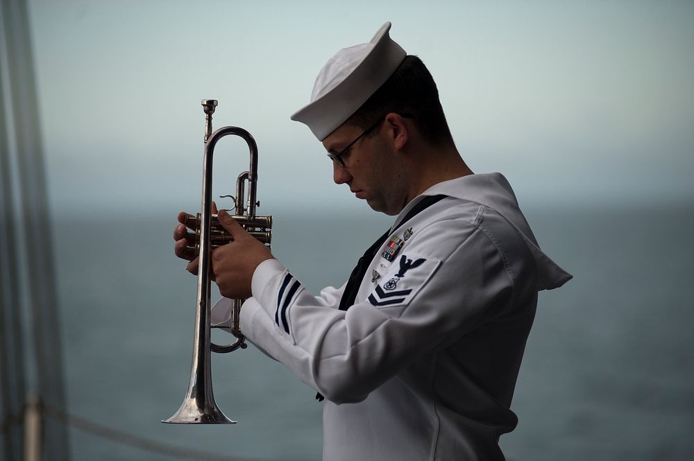 U.S. Navy Master-at-Arms Justin Wilson bows his head in prayer during a burial at sea aboard the aircraft carrier USS Carl…