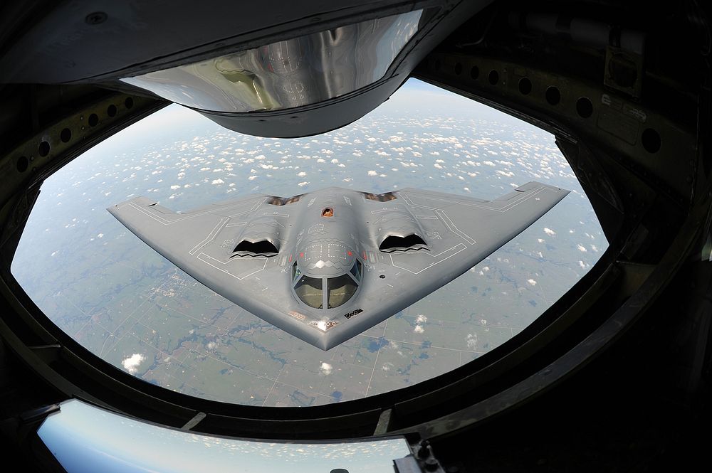 A U.S. Air Force B-2 Spirit bomber aircraft approaches the rear of a KC-135 Stratotanker aircraft before refueling during a…